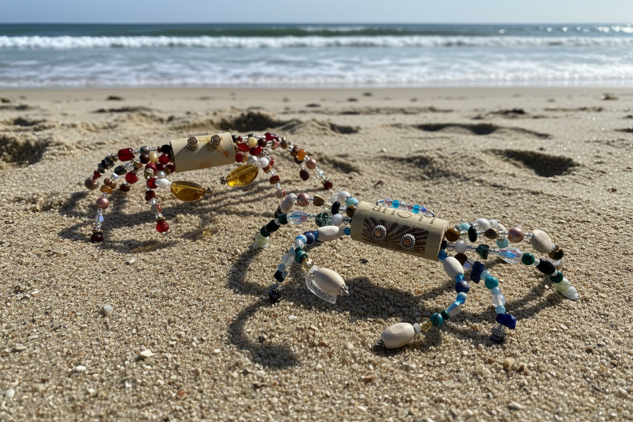 Crabs made of beads and a wine cork on a sandy beach